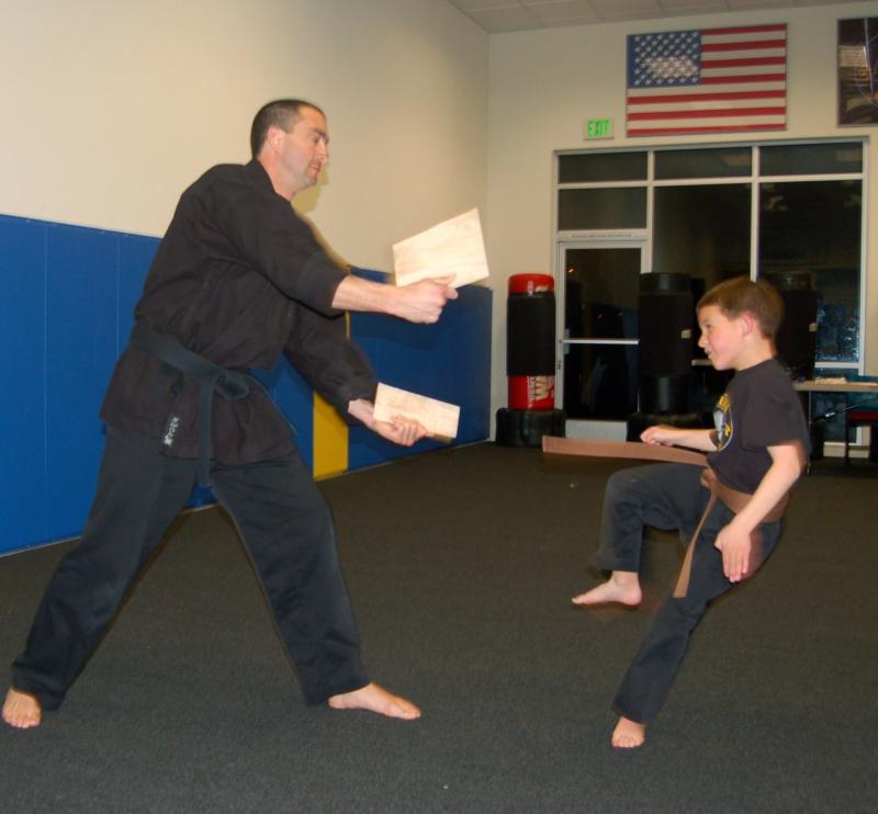 Simon breaks about board at his martial arts class.