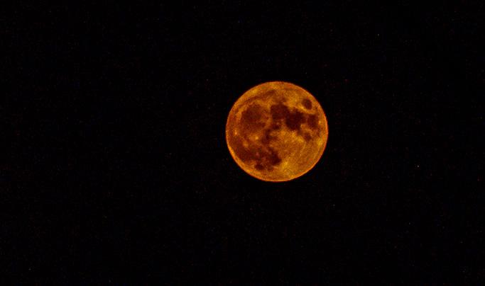 Full moon through orange soup.